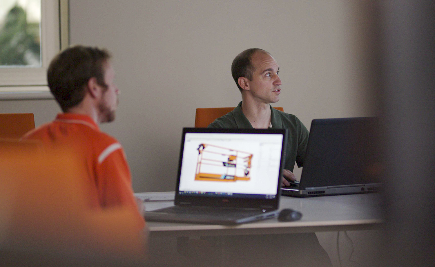 Two white male engineers working in an office on a computer