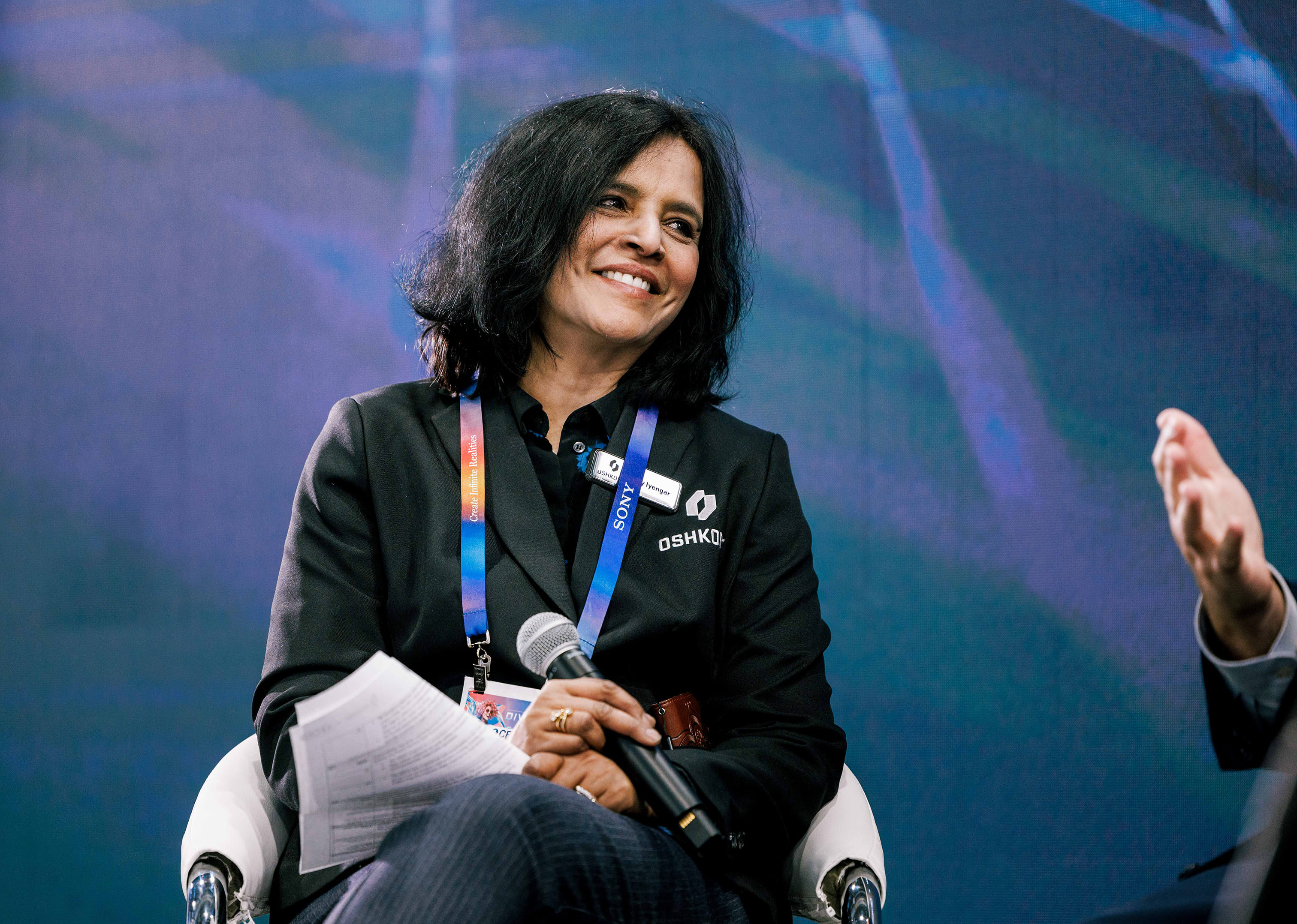 Close-up of Jay Iyengar, Oshkosh Corporation Chief Technology and Strategic Sourcing Officer, smiling during a panel discussion at CES.