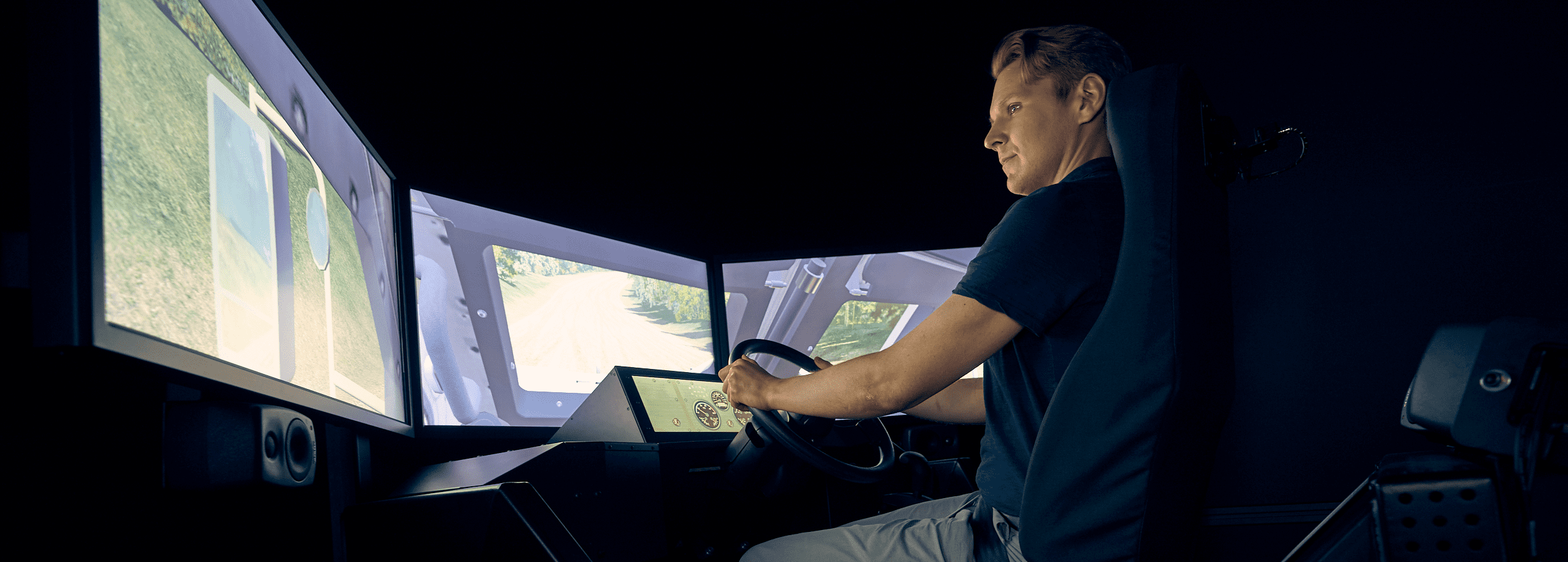 Male engineer operating a driving simulator with three tv monitors