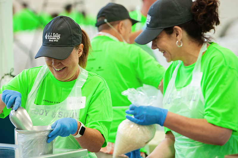 Two female volunteers at the 2024 Feed the Body, Feed the Soul packing event in Oshkosh