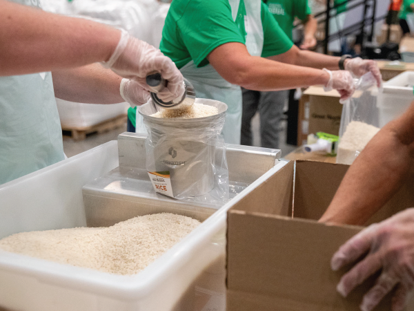 Person adding rice to a funnel during volunteer packing event