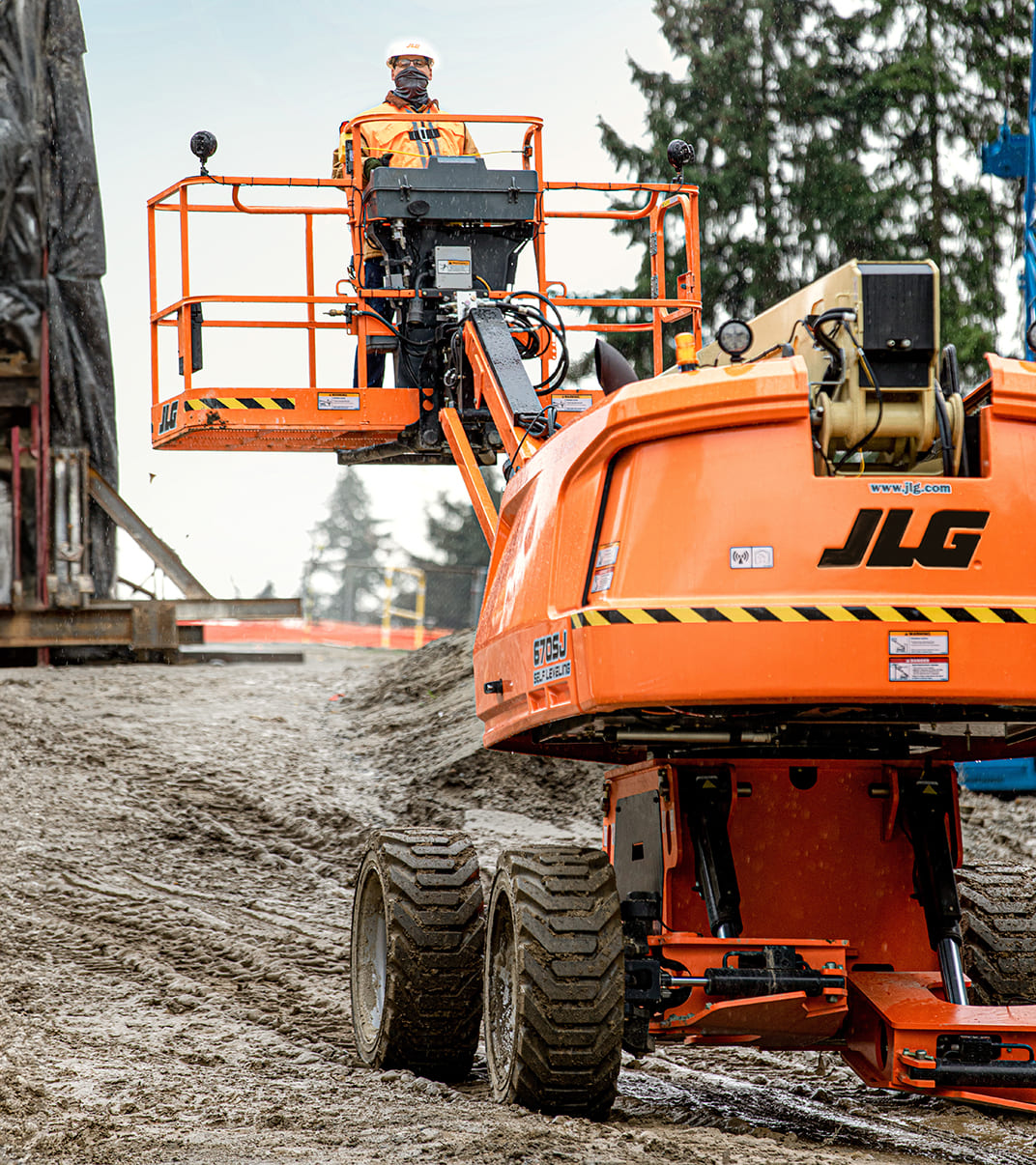Orange and cream self-leveling boom lift operating at a construction site
