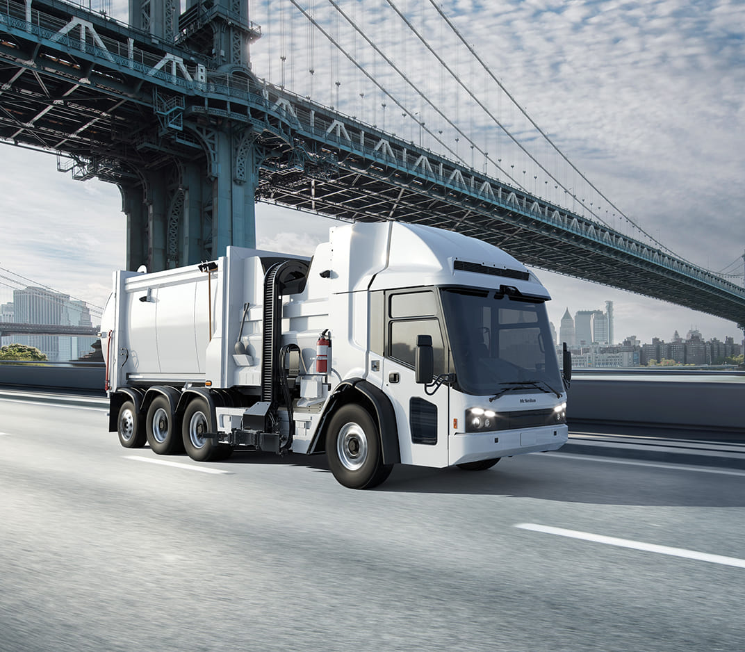 White McNeilus Volterra ZSL electric refuse collection vehicle driving on a road