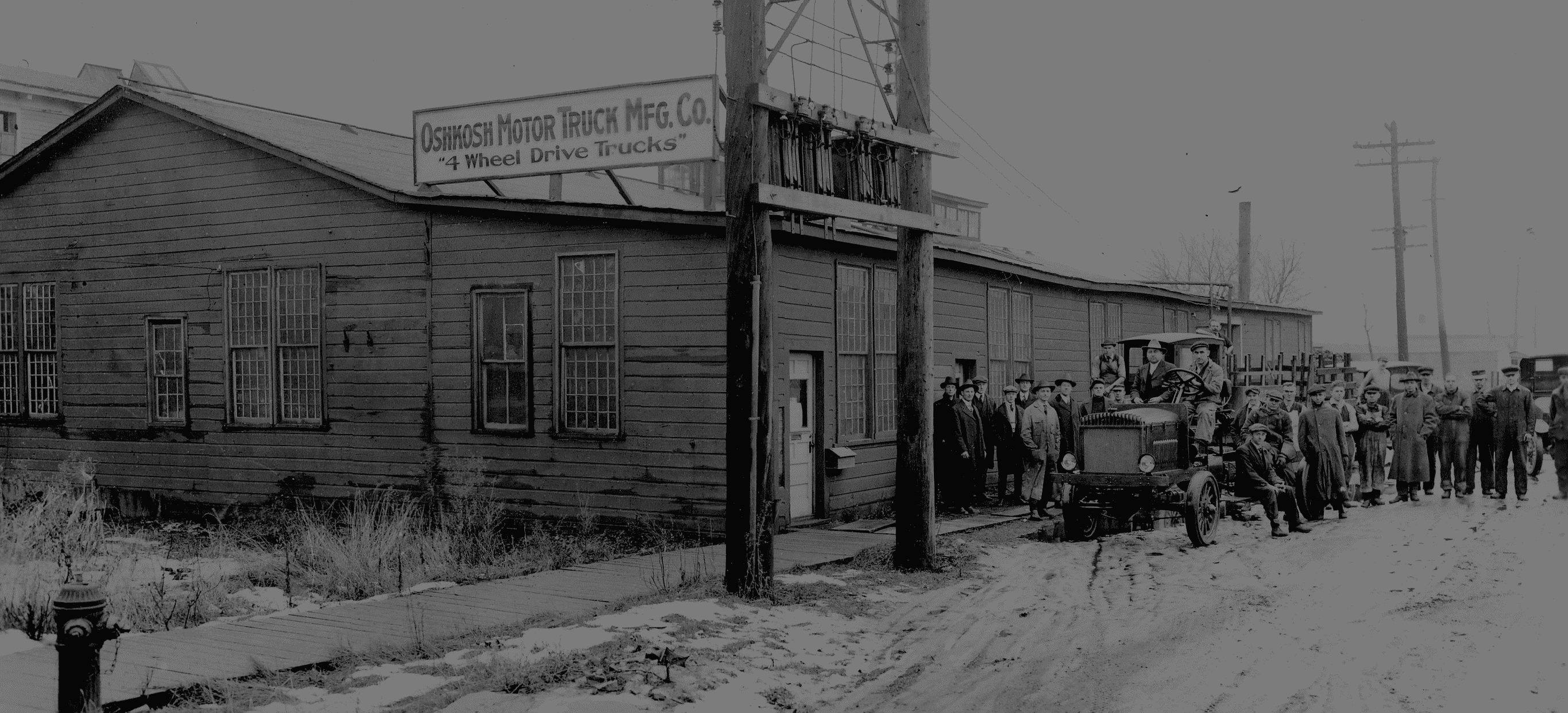 A group of people standing around a truck from the early 1900's