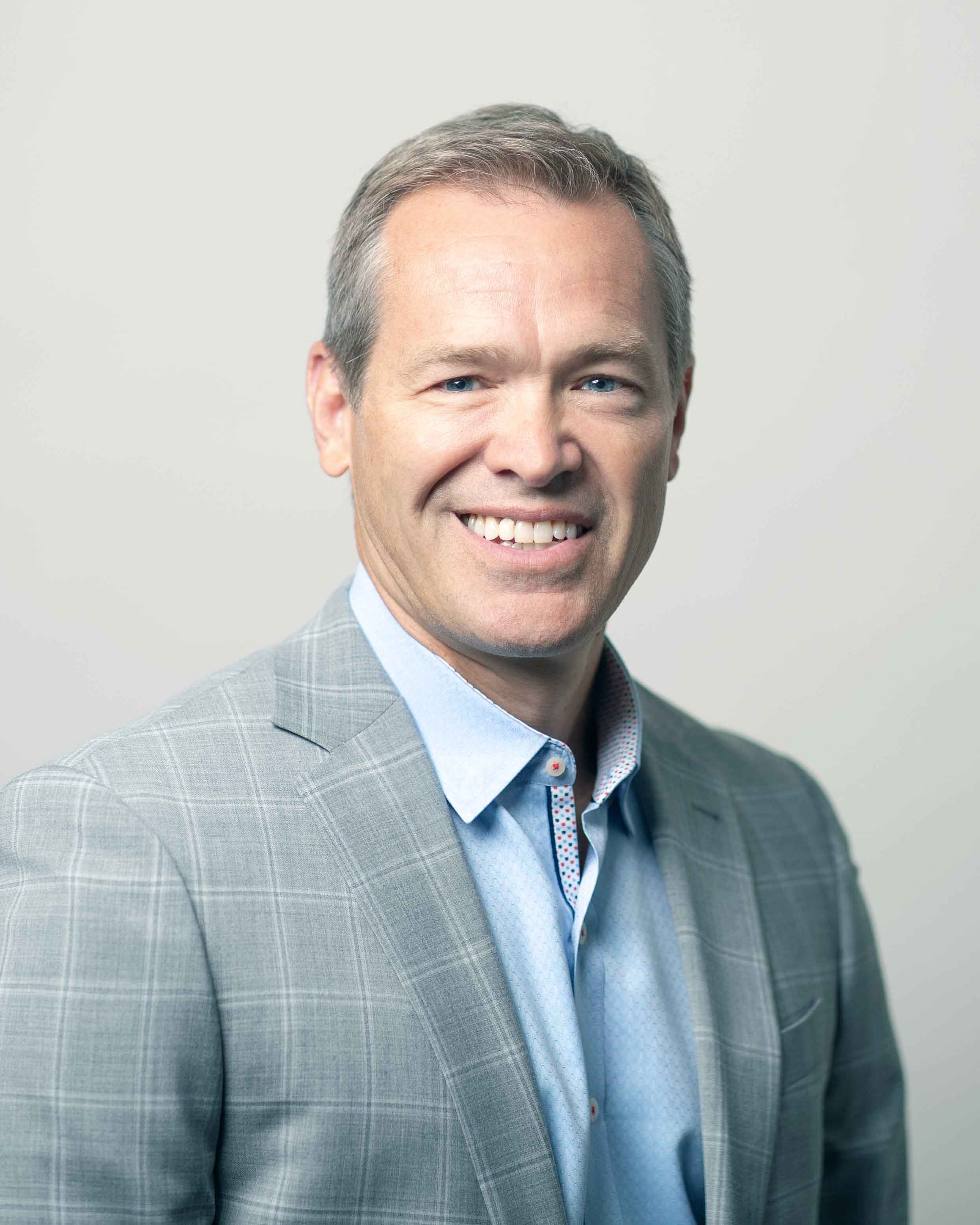 Bryan Brandt in a grey suit coat smiling