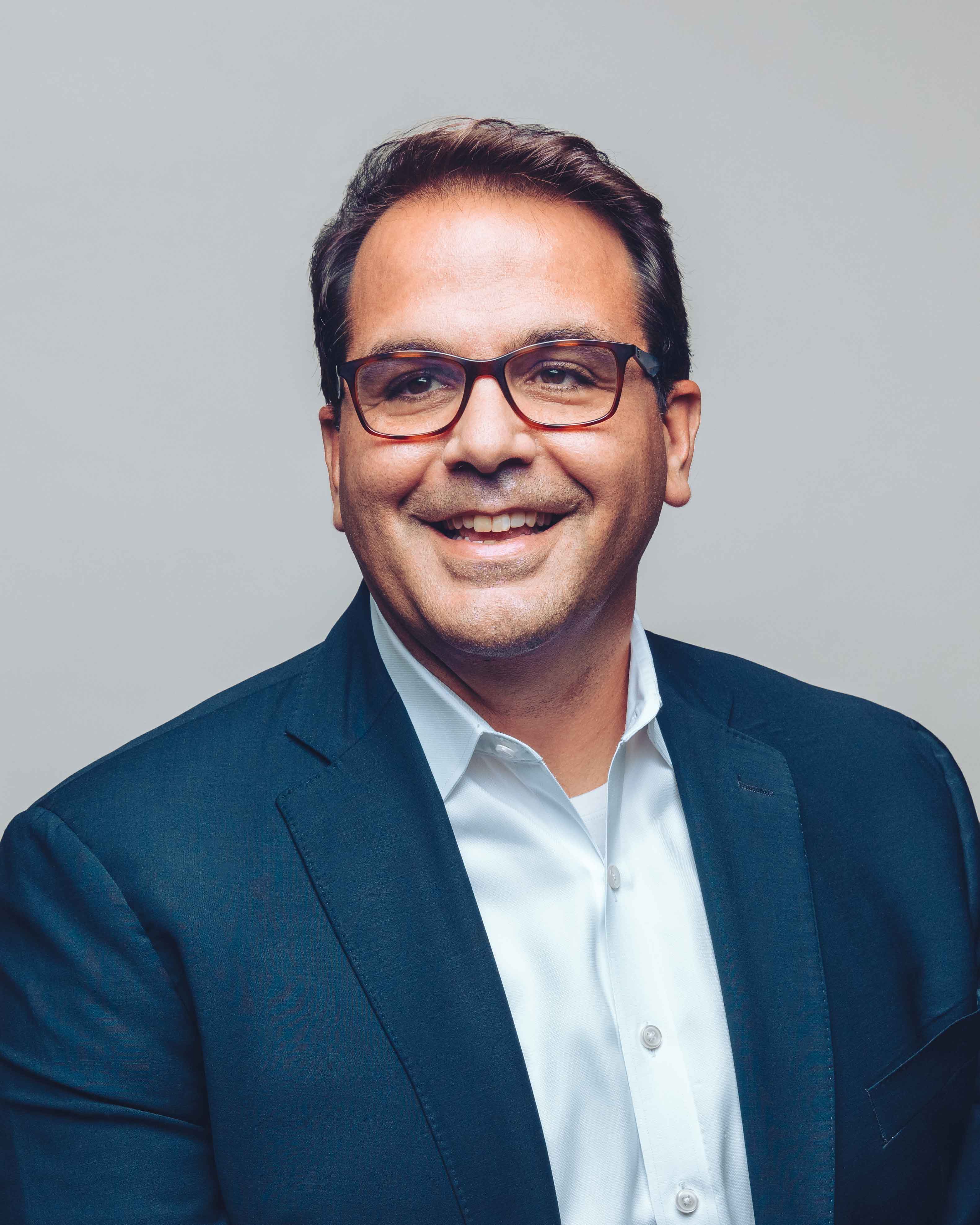 Ignacio Cortina wearing a dark blue suit coat and smiling