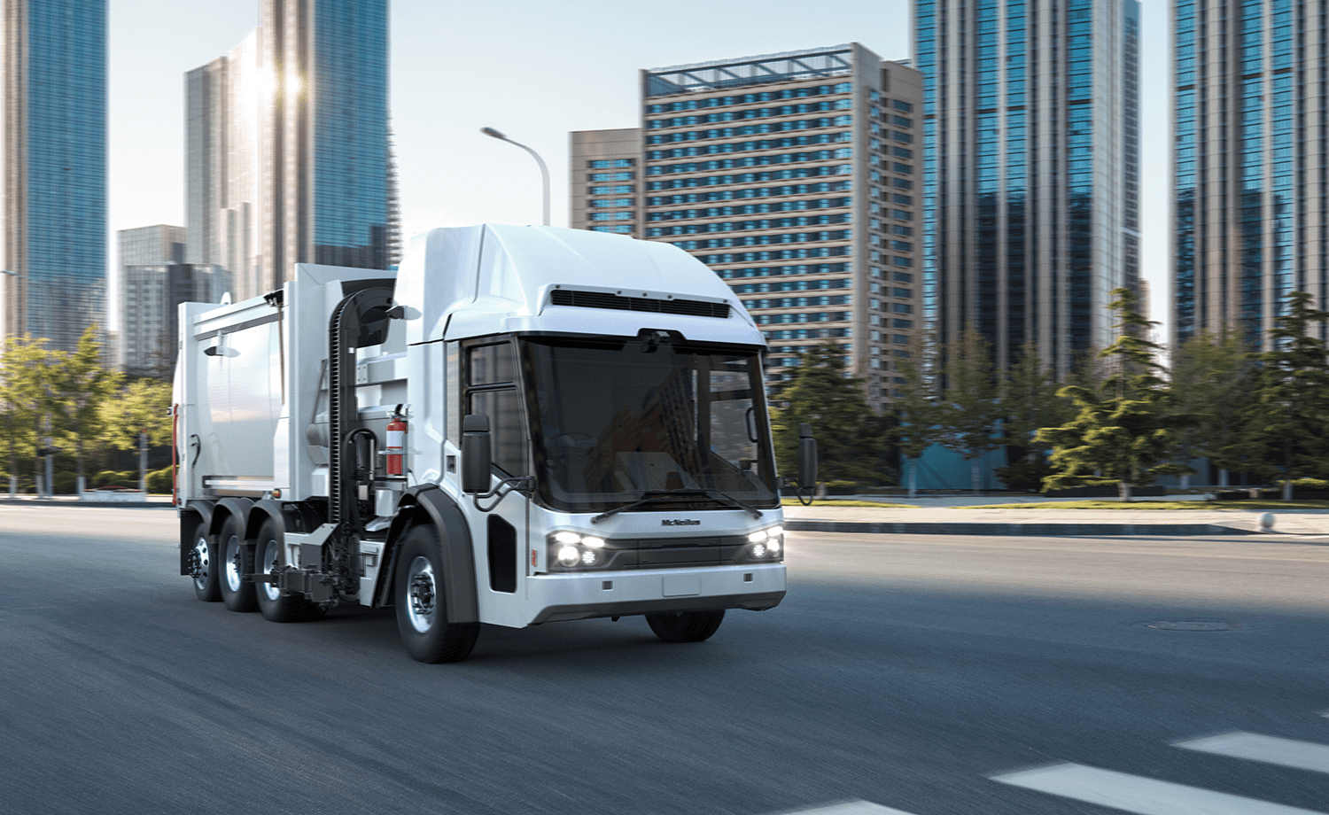 White McNeilus® Volterra™ ZSL™ electric refuse collection vehicle driving in a city