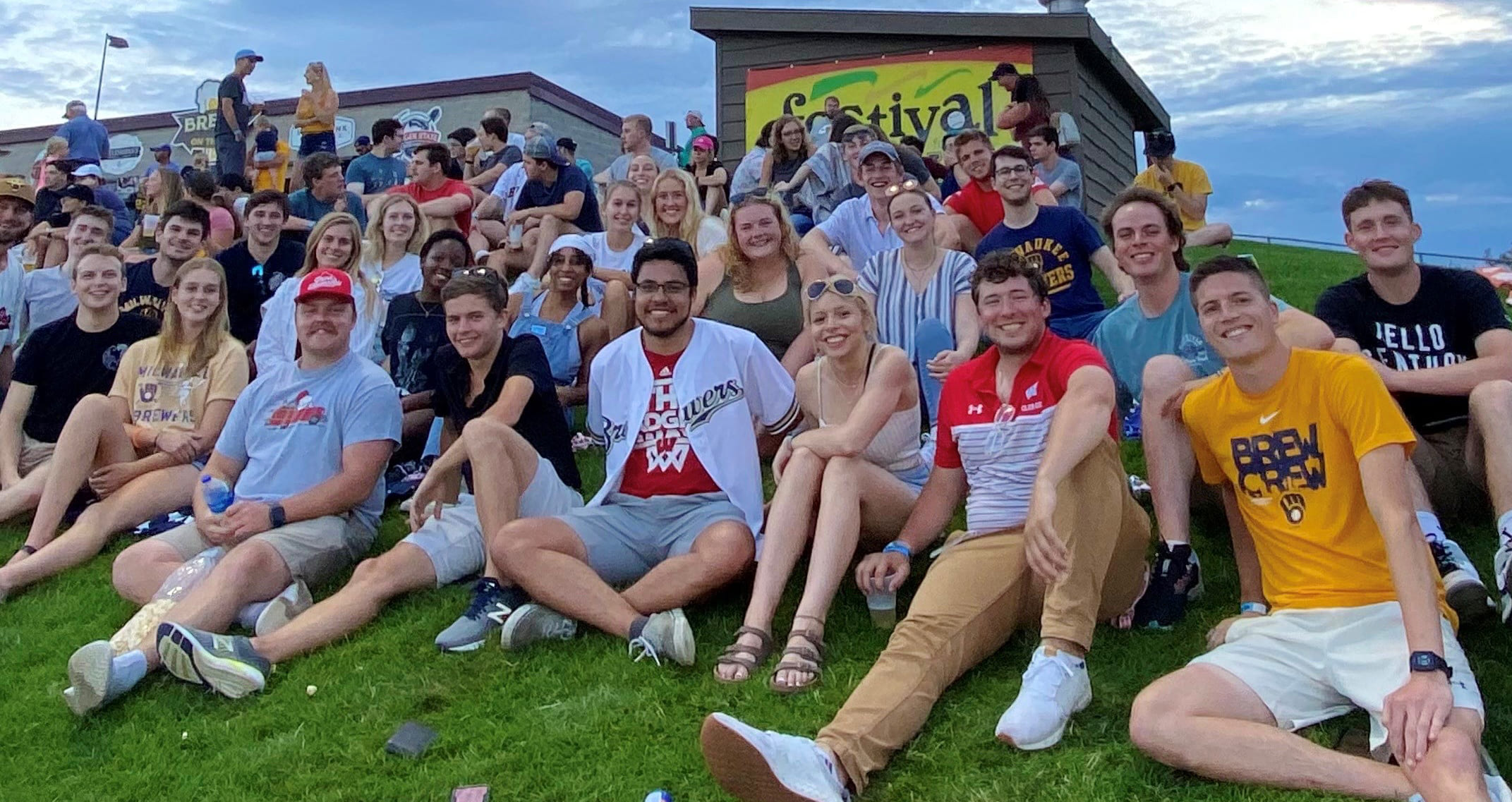  Group of students sitting in the grass at a baseball game. 