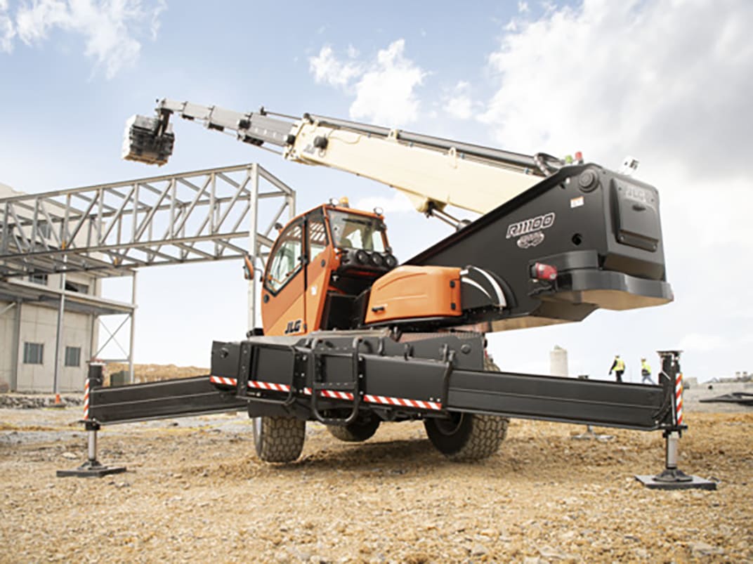Orange and cream rotating telehandler operating at a construction site